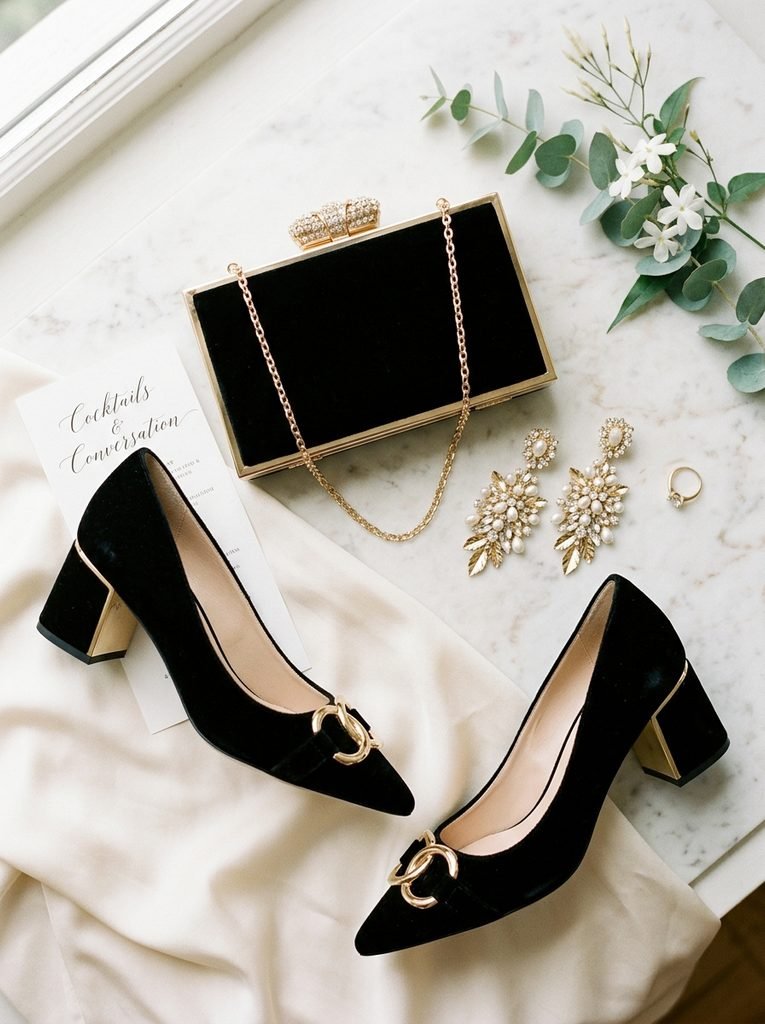 Flat lay of block heels, a structured clutch, and statement earrings for cocktail attire