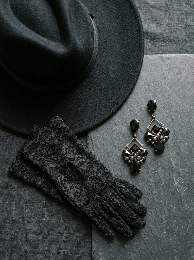 Dramatic black earrings, lace gloves, and a wide-brim hat styled as Halloween accessories