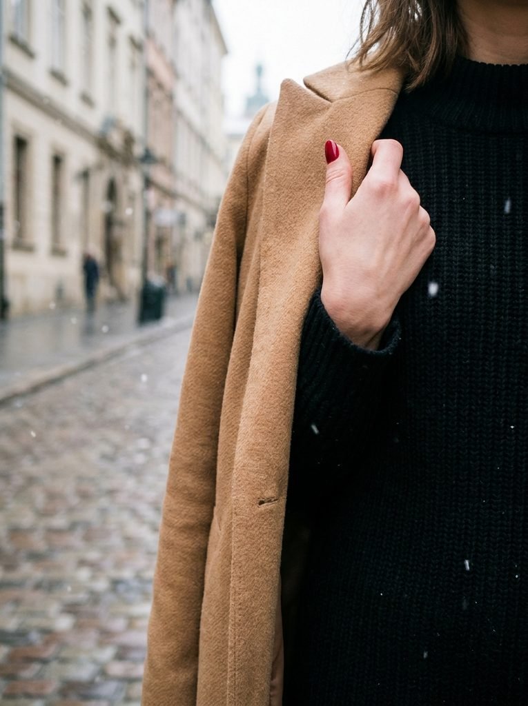 Cherry red nails on a camel wool coat collar in winter street style