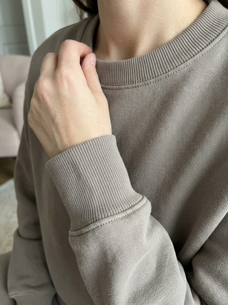 Close-up of a ribbed cuff and crew neckline on a mushroom-colored lounge set showing a polished finish
