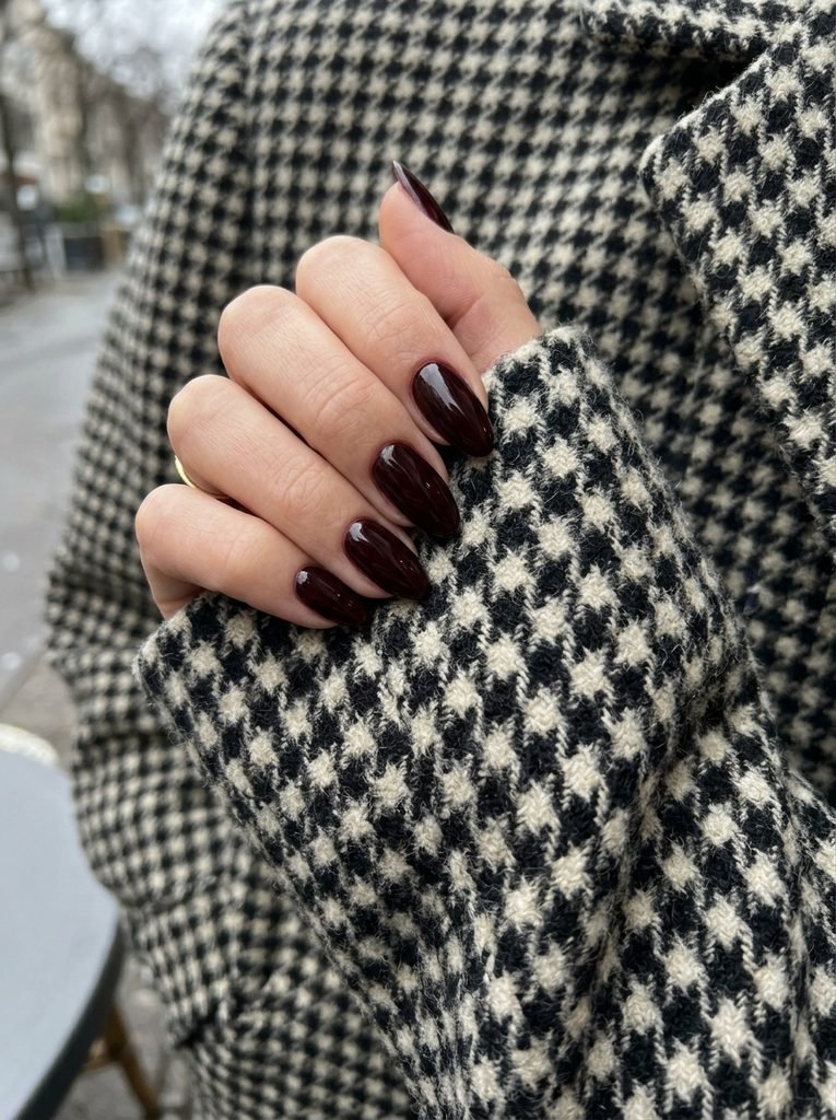 Black cherry nails against a houndstooth wool coat sleeve