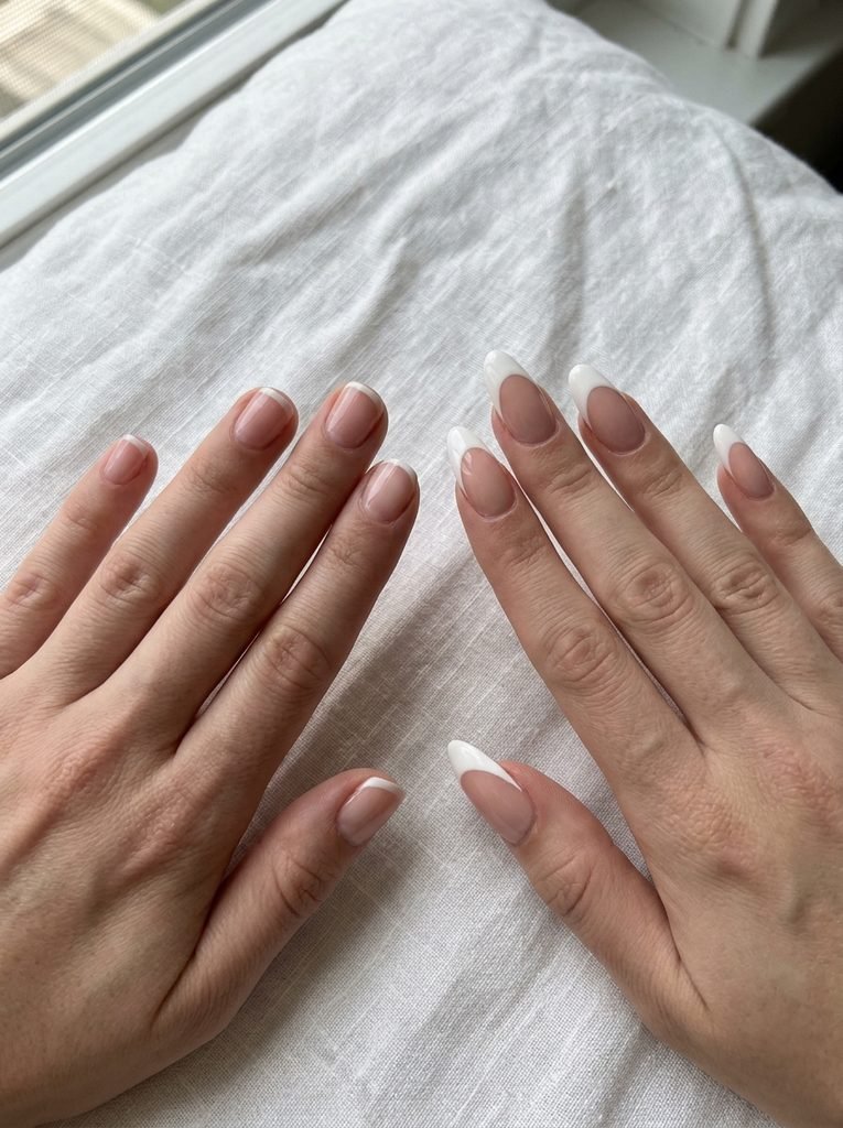 Short and long nails comparing French tip depth on a white linen surface